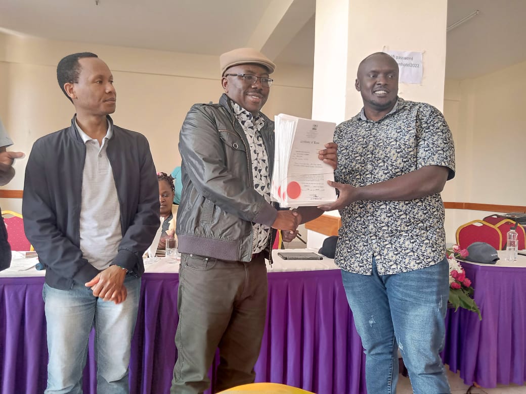 Samuel Maina hands over title deeds to Hilary Maingi, Chair, Panorama Garden's Residents Association.